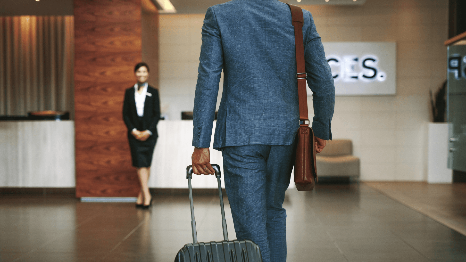 Corporate traveller arriving at a hotel reception with a suitcase
